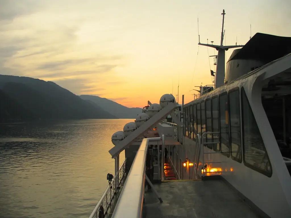 The rear deck of the Alaska ferry Columbia at sunset, with a calm channel and forested hills beyond