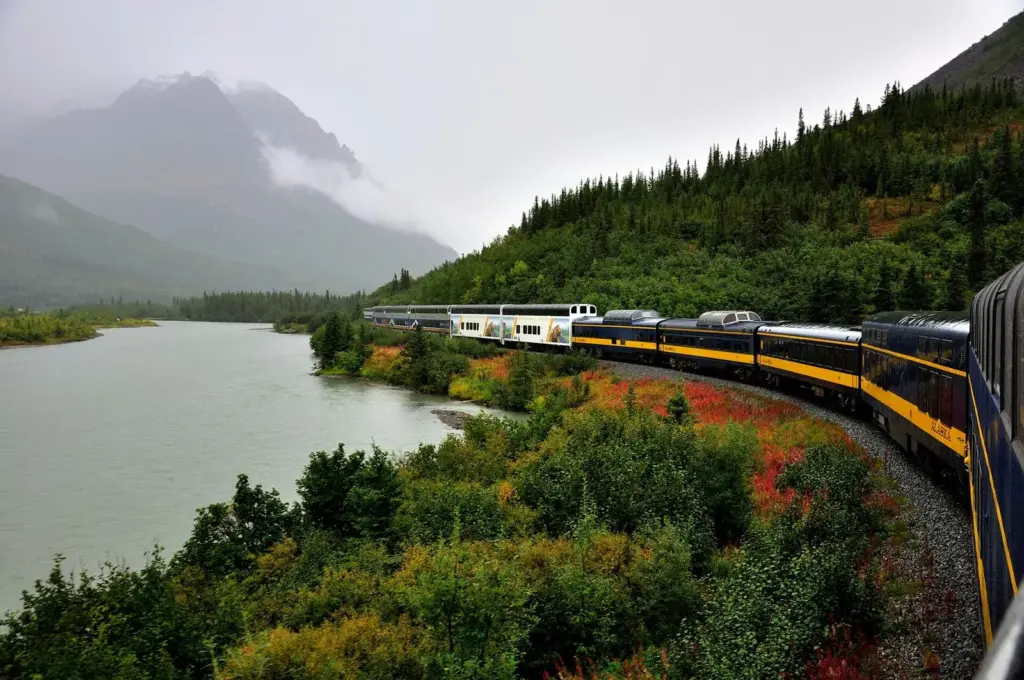 The Alaska Railroad's Denali Star train rounding a curve beside a river below forested hills