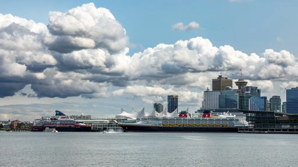 Cruise ships docked at Canada Place in Vancouver beneath the terminal's white sail-shaped roof and downtown towers