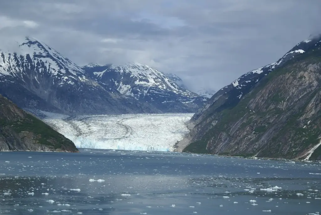 Dawes Glacier filling the head of Endicott Arm between steep granite walls, with small icebergs floating in the fjord