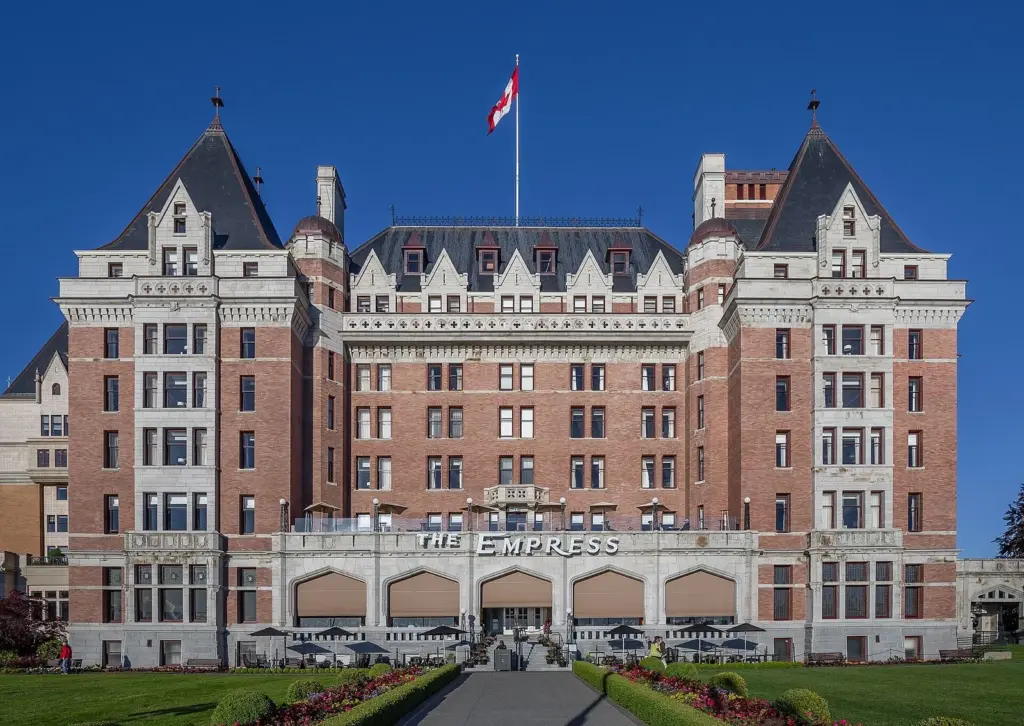 Red brick facade and steep roofs of the Fairmont Empress hotel behind its front lawn