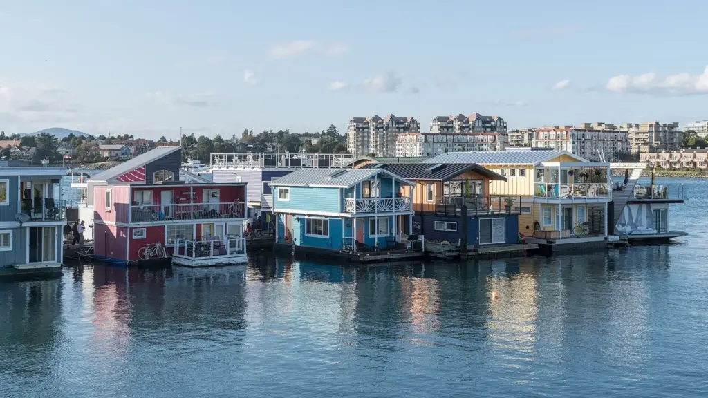 Colorful float homes moored at Fisherman's Wharf in Victoria with apartment buildings behind