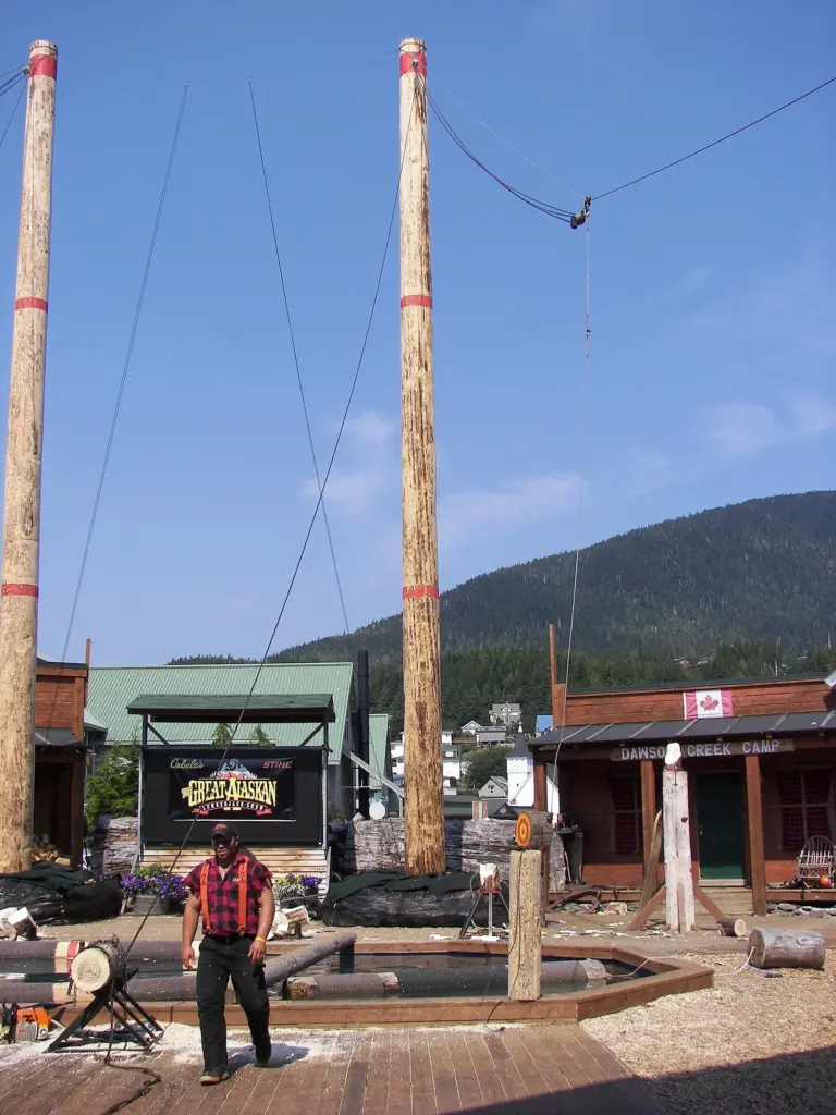 The Great Alaskan Lumberjack Show arena in Ketchikan with two tall climbing poles and a lumberjack at the center