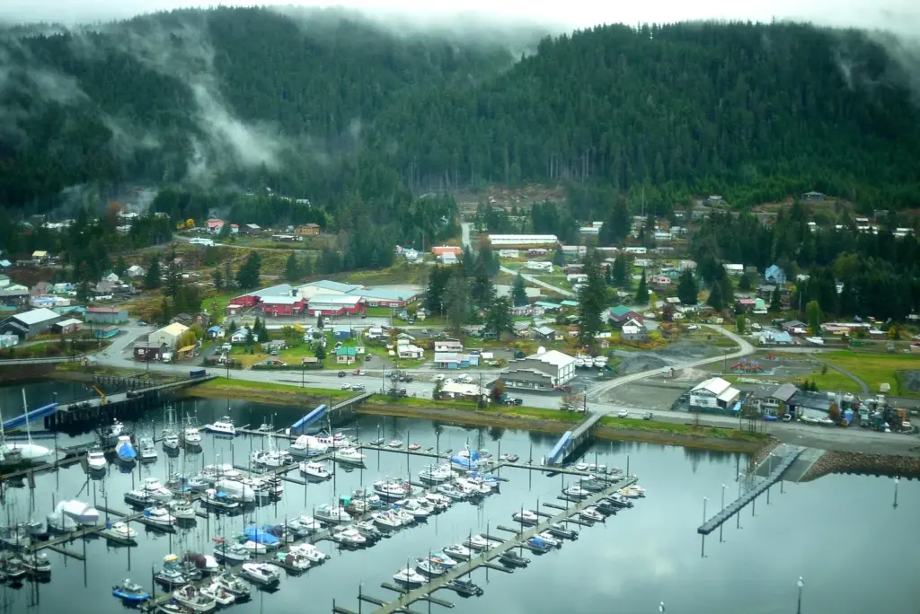 Aerial view of Hoonah with its boat harbor, houses and forested hills in low cloud