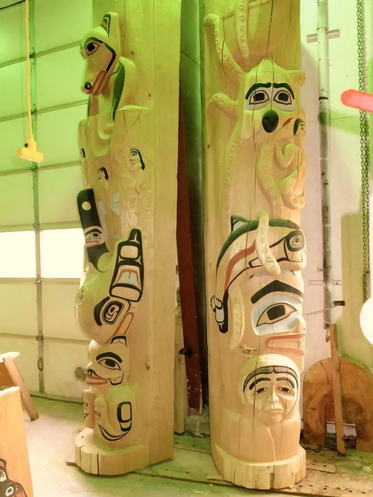Carved and painted house posts standing inside a carving shed in Hoonah