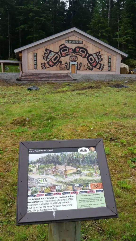 Carved and painted cedar front of the Huna Tribal House in a clearing at Bartlett Cove