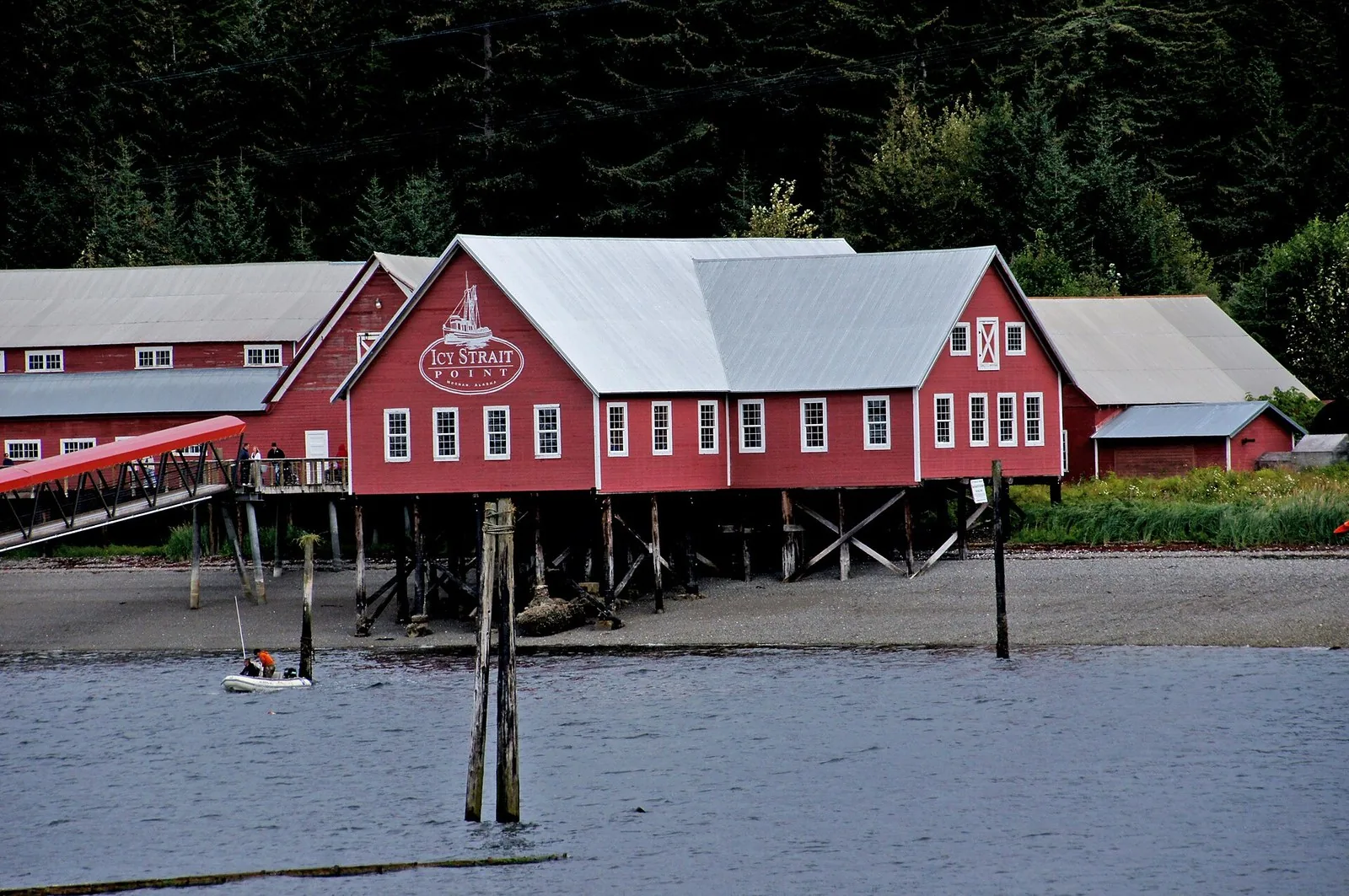 Red cannery buildings on pilings with the Icy Strait Point sign above the water at Hoonah