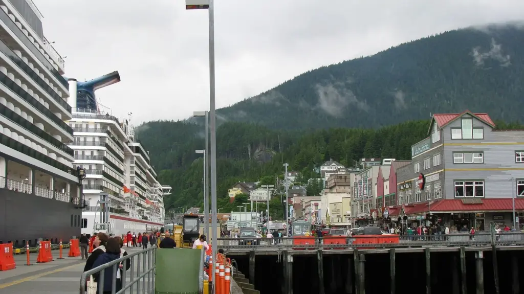 Cruise ships docked right alongside the Ketchikan waterfront street, with shops, passengers and forested hills behind