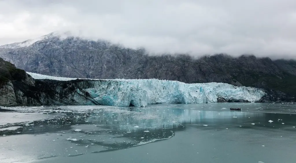 Margerie Glacier's broad blue-white face meeting the water under low cloud