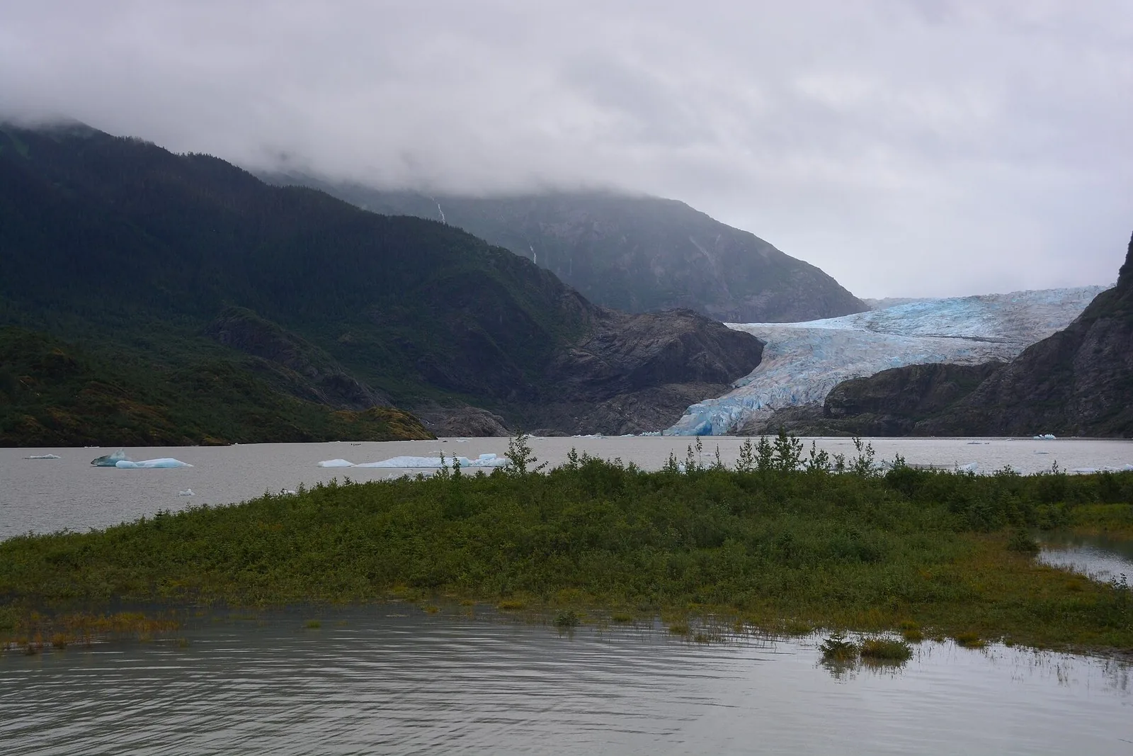 Mendenhall Glacier seen across Mendenhall Lake from the Photo Point viewpoint below cloud-wrapped mountains