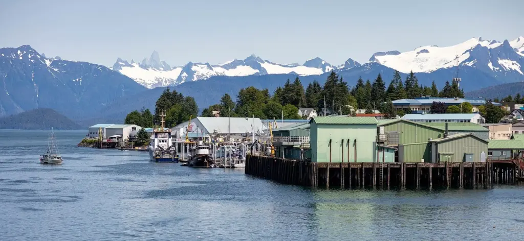 Petersburg waterfront with canneries on pilings, boats and snowy mountains behind
