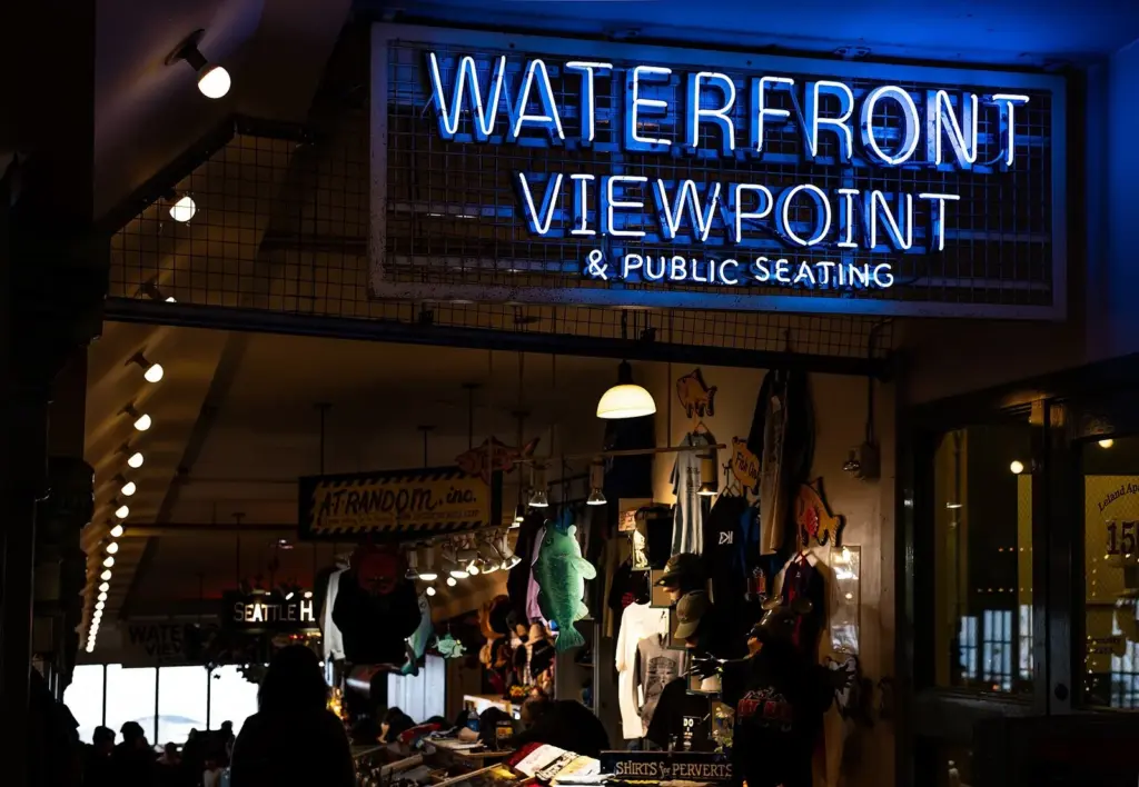 A lit neon sign reading Waterfront Viewpoint and Public Seating inside Pike Place Market in Seattle