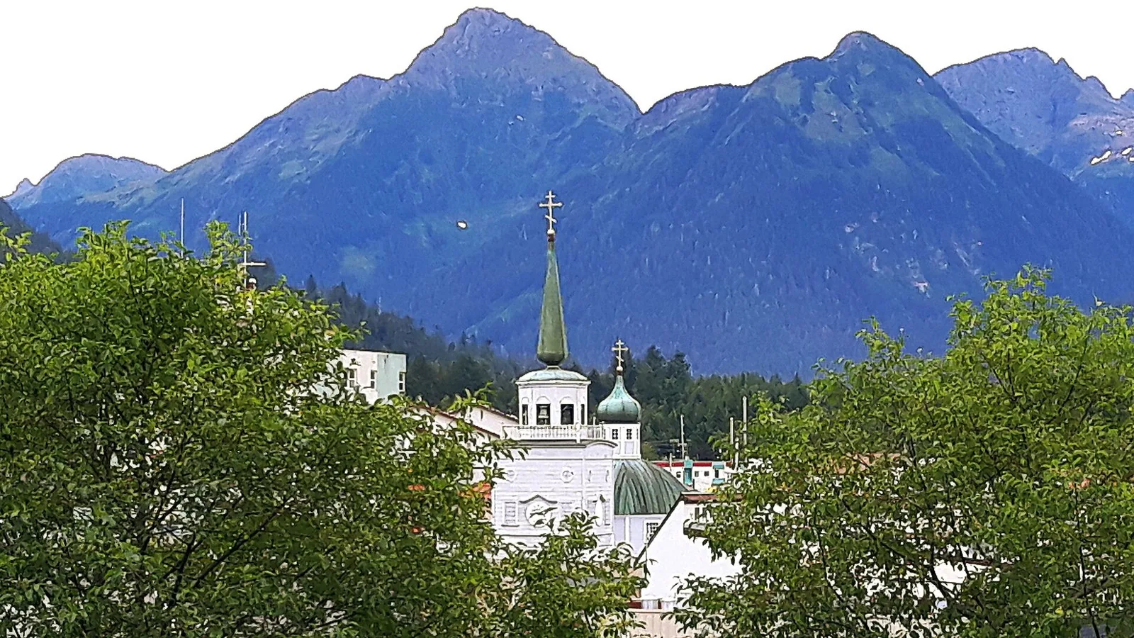 Onion domes of St. Michael's Cathedral seen from Castle Hill with mountains behind, among the top things to do in Sitka