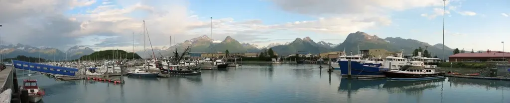 Panorama of the Valdez small boat harbor with fishing boats and mountains behind